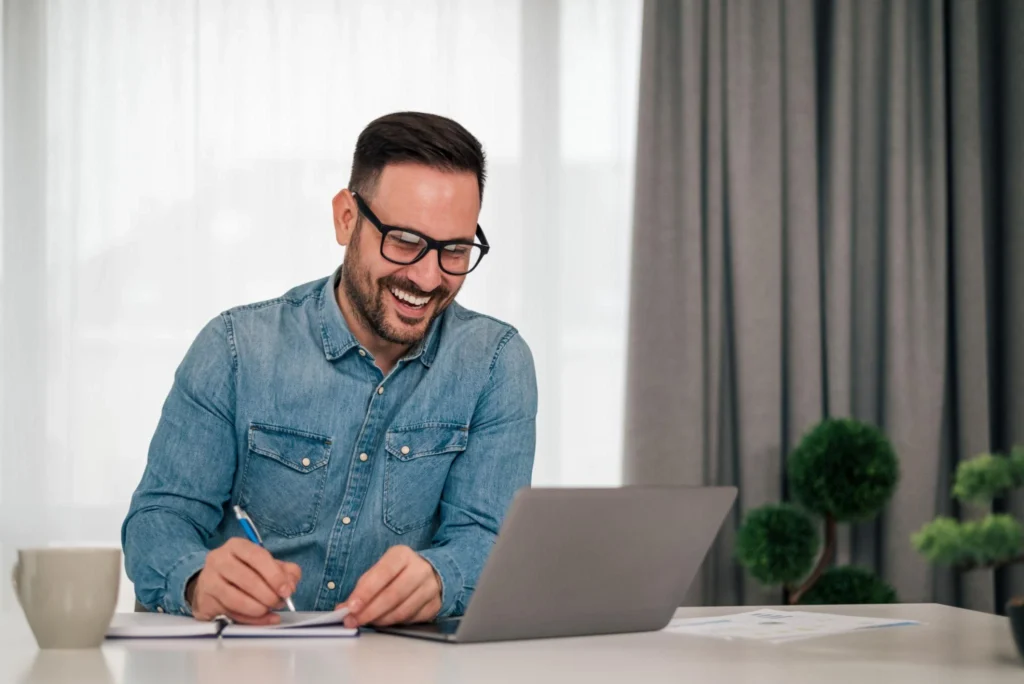 Business owner working on laptop and writing notes in a clean workspace, representing stress-free accounting and bookkeeping services.